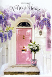 This photograph portrays a Cranford home entrance where flowers, colour, and architecture come together to tell a gentle story of arrival and belonging. A pastel pink front door anchors the image, its softly painted surface carrying a muted sheen that suggests recent care and a fresh start. Surrounding the door, whitewashed walls and a pale shutter provide a clean, bright backdrop, reminiscent of the tidy façades seen along Cranford's quiet residential streets and those leading towards the tranquil green expanse of Cranford Park. Above, a flourishing wisteria pours downward in cascading trails of lavender and lilac blooms, each slender raceme made up of tiny, bell-like petals. The wisteria frames the entrance with a romantic sweep, its clusters hanging at varying lengths that create layers of shadow and light. Nestled on the doorstep is a stylish grey tin bucket repurposed as a rustic vase, filled to the brim with creamy white roses. The roses are plush and generous, with velvety petals arranged in tight spirals and open cups, interlaced with sprigs of fresh green foliage that peek out around the edges. A satin pink ribbon is tied around the bucket's base, its soft gleam echoing the door's pastel tone and gently unifying the composition. Light filtering through the wisteria's leaves dapples the step and the lower part of the door, suggesting a calm afternoon in Cranford when time seems to slow. The atmosphere is tender and hopeful, capturing the feeling of walking up to a new front door for the first time, greeted by flowers that quietly say, You're home, and you're welcome here. Crafted with the eye of an experienced local florist, it's an image that pairs perfectly with a housewarming message or congratulations on a fresh chapter in Cranford.